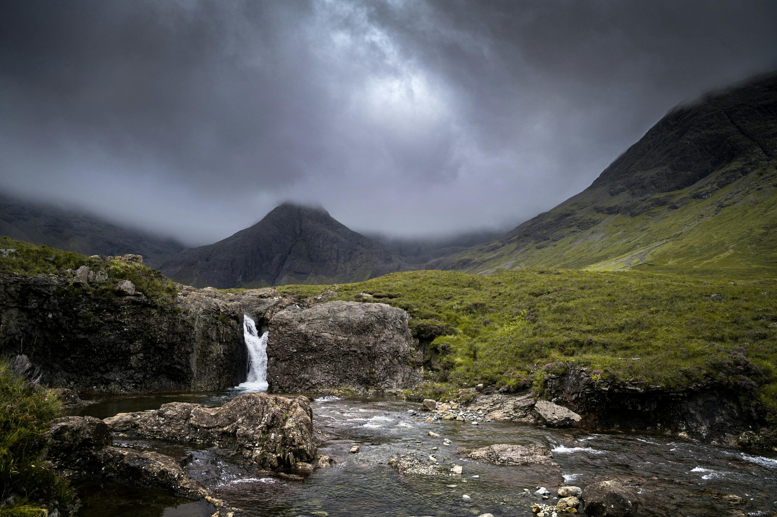 Moody scenery of a waterfall in the Isle of Skye under storm clouds along the walk at the Fairy Pools, Glenbrittle