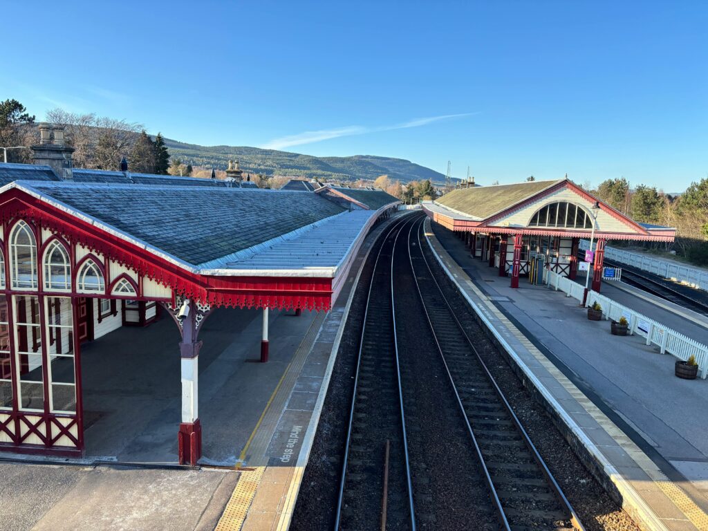 A scenic view of Aviemore train station surrounded by mountains in Scotland.