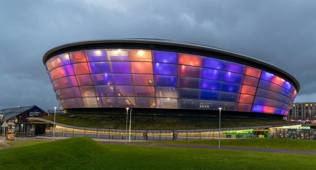 Vibrant night view of the Ovo Hydro in Glasgow, Scotland, with illuminating colors. Ready for the Commonwealth Games Glasgow 2026.